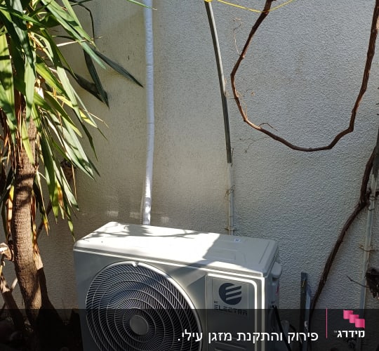 יחידת מזגן חיצונית מותקנת על קיר עם צינור לבן
